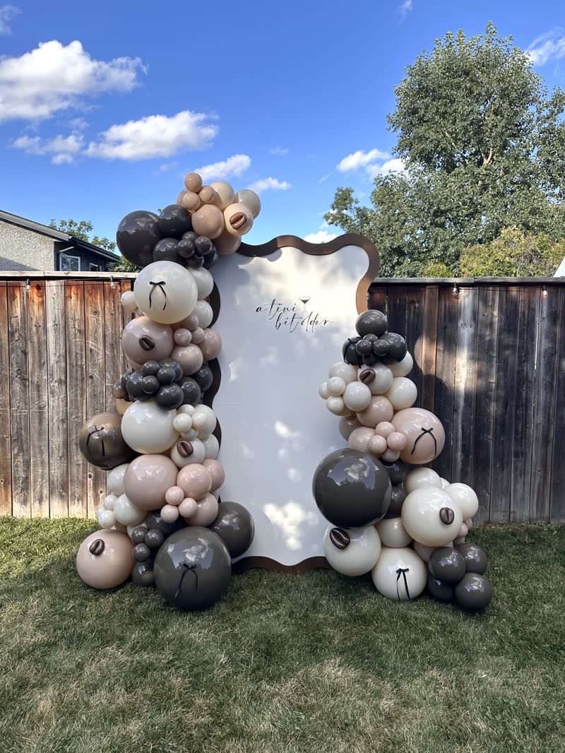 Football-themed balloon garland on an outdoor backdrop panel, Winnipeg