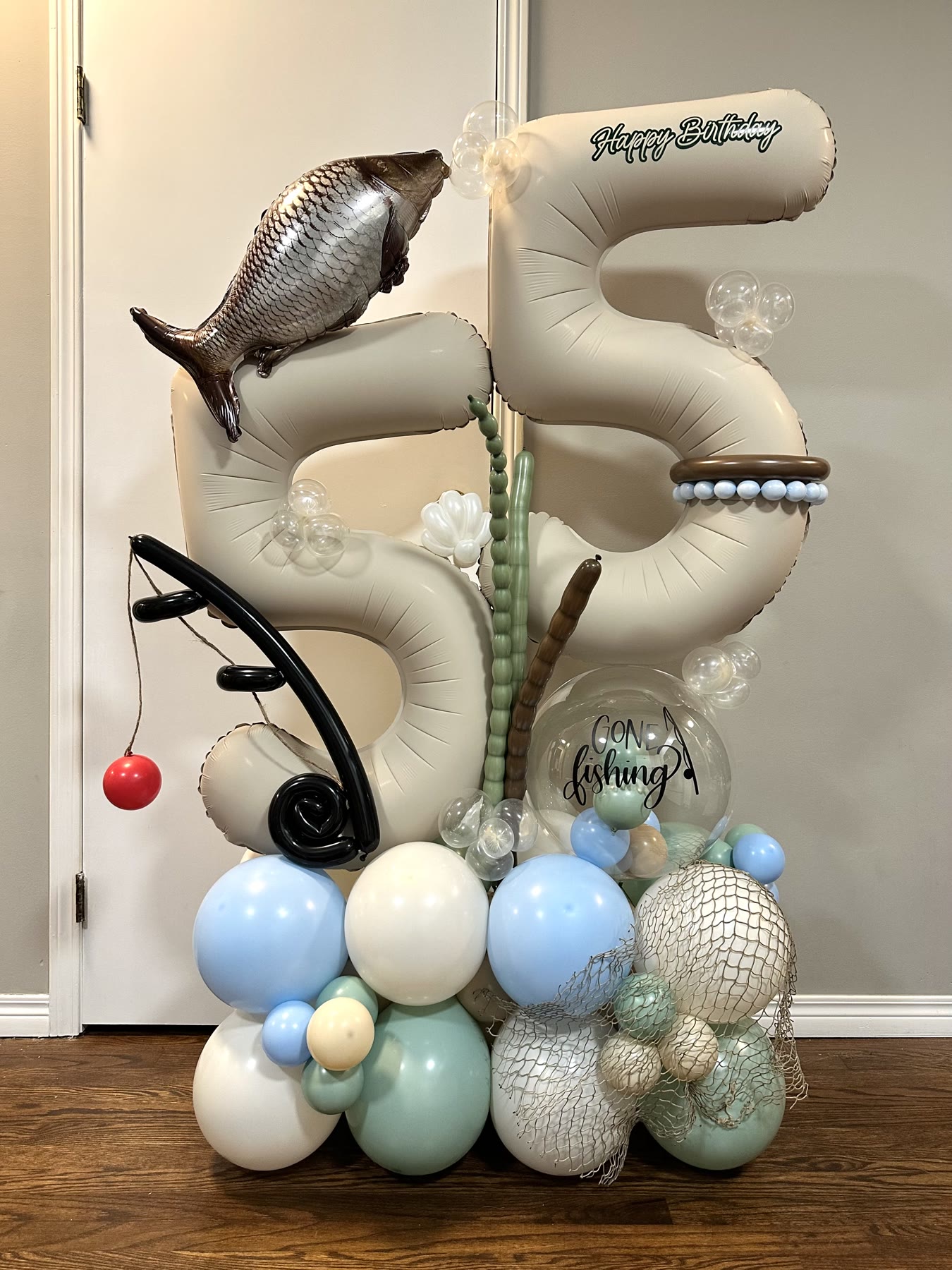 Giant 55 balloon number stack with fishing-themed accents for a milestone birthday in Winnipeg