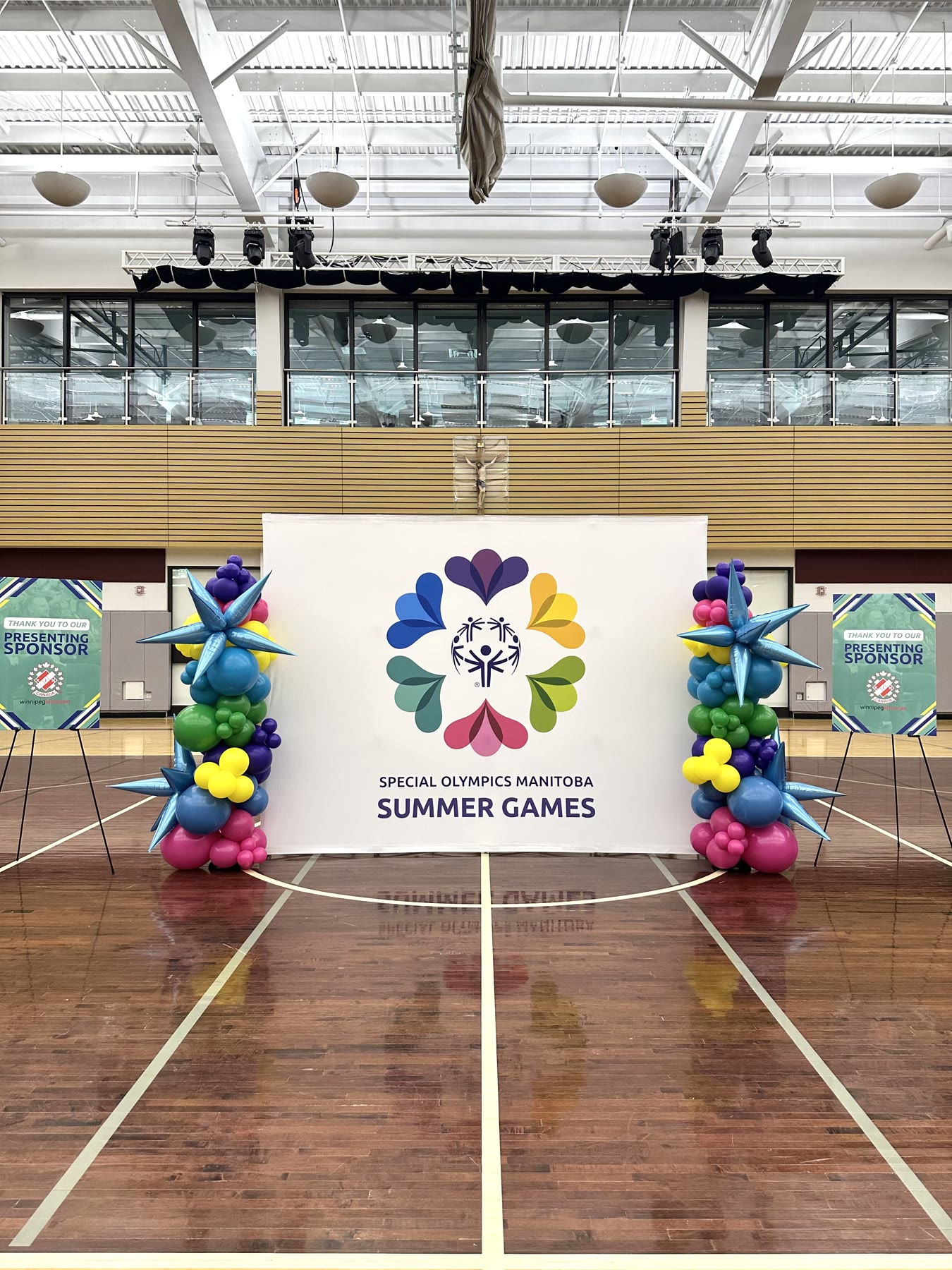 Matched balloon columns flanking a sponsor backdrop at a Special Olympics Manitoba Summer Games event in Winnipeg