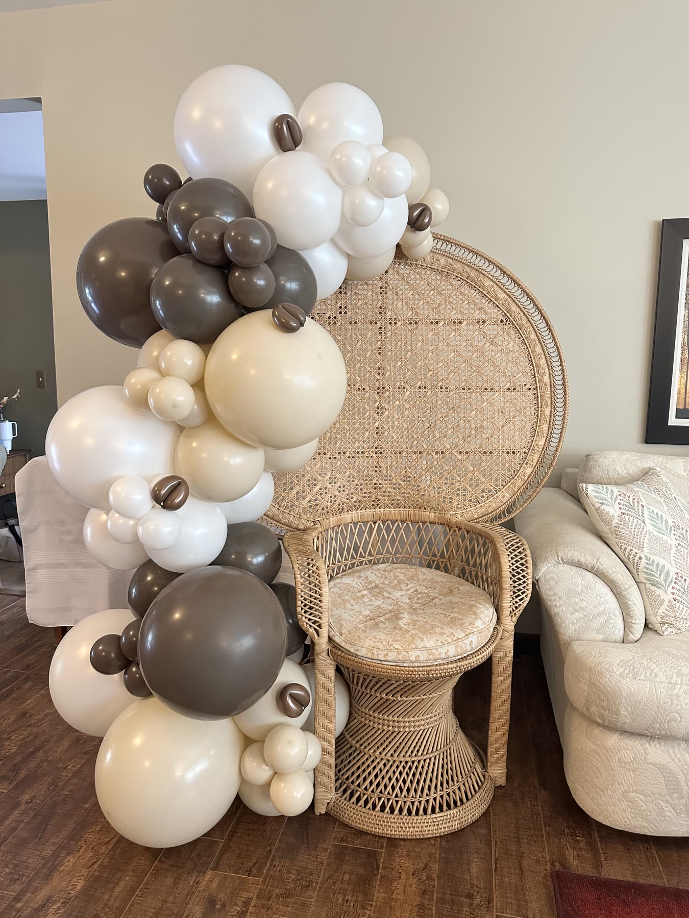 Brown, cream and white balloon garland beside a rattan peacock chair in a Winnipeg living room